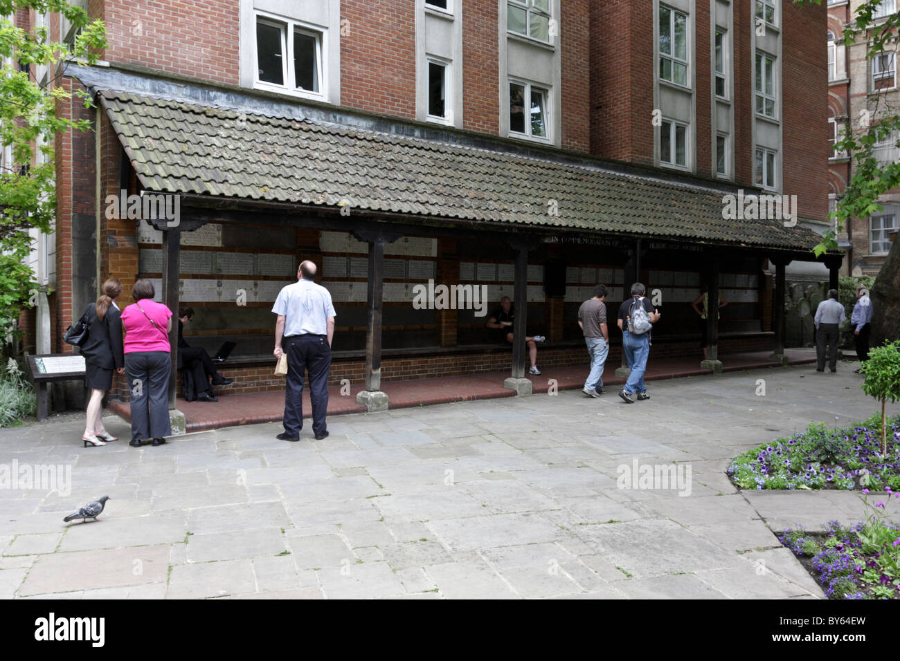 Members of the public look upon the memorial tiles in Postman`s Park in the City Of London. Stock Photo